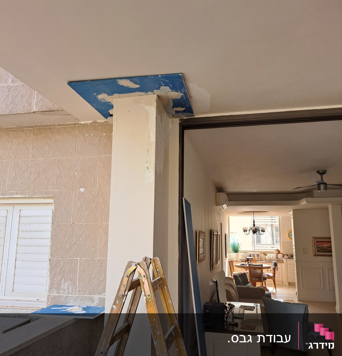 סולם עץ ליד קיר עם לוח גבס כחול